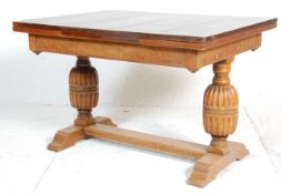 An early 20th Century oak draw leaf dining table having a rectangular top on bulbous cup and cover