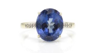 A 9ct white gold Birmingham hallmarked blue stone and diamond ring. THe central oval mixed cut