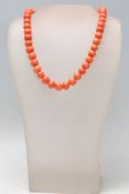 A 20th Century coral beaded necklace having spherical beads strung on a spring ring clasp.