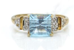 A 9ct gold  / 375 marked diamond and blue topaz ring. The cushion cut topaz with diamond set
