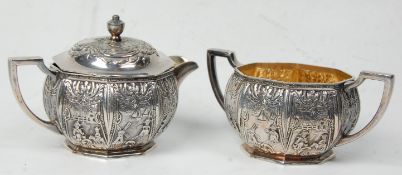 A matching silver plated creamer jug and lid sugar bowl having twin handles. Both repousse decorated