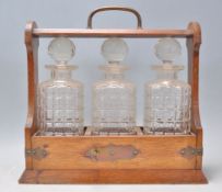 A 20th Century wooden drinks tantalus cabinet holding three cut glass decanters complete with