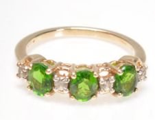 A 9ct gold diamond and green stone ring. The three oval mixed cut green stones with diamond prong