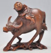 An early 20th Century Chinese carved hardwood figurine in the form of a man riding a water buffalo