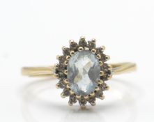 A 9ct gold and aquamarine ring. The ring with oval cut aquamarine within a halo of diamonds to