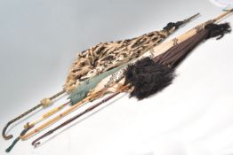 A collection of antique parasols / umbrellas, two having bamboo handles, one with a lace canopy