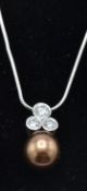 A 9ct white gold snake chain strung with a freshwater dyed brown pearl and diamond pendant.