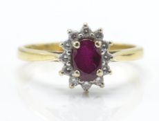 A hallmarked 18ct gold ruby and diamond cluster ring. The ring set with a central mixed cut oval
