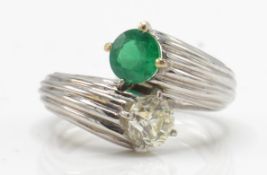 An emerald and diamond toi et moi ring. Estimated diamond weight 0.70cts
