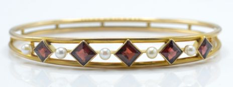 A gold pearl and garnet set bangle. The bangle set