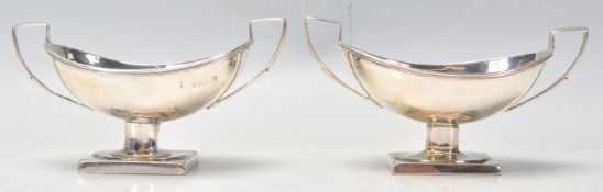 A pair of silver hallmarked salt cellars having twin square handles raised on square plinth bases (