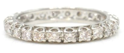 A white gold and diamond eternity ring. The ring with inset 24 round cut diamonds, estimated diamond
