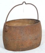 A late 19th Century Victorian iron cooking pot / cauldron having a large swing handle with hook