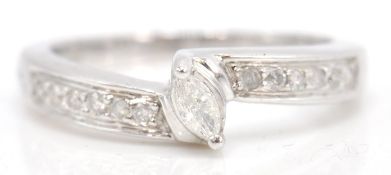 A stamped 9ct white gold ring set with a marquise cut diamond flanked by diamond accent stone