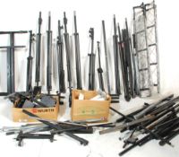 A large group of multiple pairs and single speaker stands and microphone stands with most being