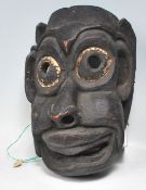 A Himalayan / Nepalese folk art carved wooden shaman's mask in the form of a stylised ebonised human