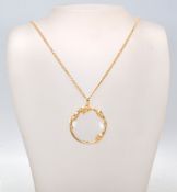 A yelllow metal 20th century large puzzler - magnifying glass pendant on langard necklace chain. The