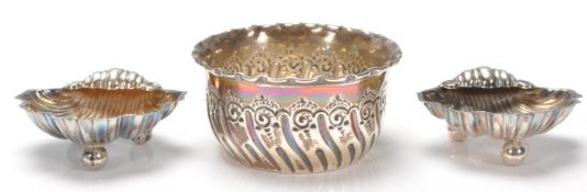 A pair of silver hallmarked Edwardian salt cellars in the form of scallop shells raised on three