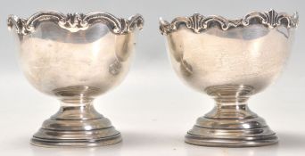 A near pair of early 20th Century silver footed bowls each having raised scrolled design raised