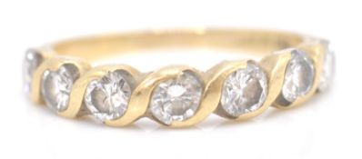 A stamped 750 18ct gold ladies ring having a twist design set with seven round cut white stones.