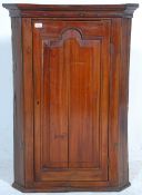 A 19th century fruitwood George III corner cabinet. Full length fielded panel door with enclosed