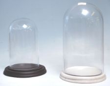Two vintage glass display domes dating from the early 20th Century with both raised on circular