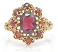 A 9ct gold hallmarked cluster ring. The ring set with oval facet cut garnet within a pierced setting