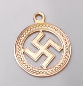 A hallmarked 9ct yellow gold swastika pendant in an oval setting with engraved decoration.