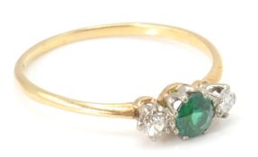 An 18ct gold diamond and green stone - 3 stone ring. The ring set with a central round mixed cut