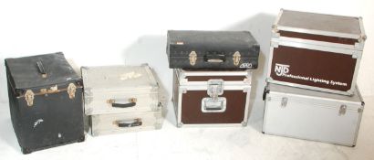 A group of seven music equipment carry case with most being flight cases and some bearing makers