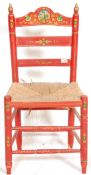 A folk Art / Barge Ware type low chair having a rush seat finished in red with floral and gilt