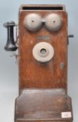 An early 20th Century wall mounted telephone being oak cased with Bakelite mouth and earpiece.
