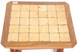 A vintage retro 1970's teak wood nest of three tables having beige tiled tops with twin supports