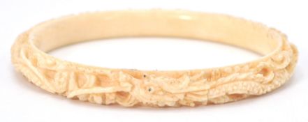 An antique early 20th Century Chinese finely carved ivory bangle with a repeating dragon motif.