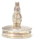 A silver hallmarked pill box of oval form having a small figure in the form of Peter Rabbit.