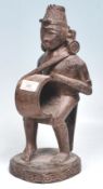 A 20th Century carved African hardwood tribal figurine in the form of a man with a drum having a