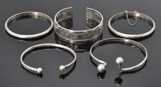 A good group of five silver bangle bracelets to include a Egyptian bangle having engraved panels