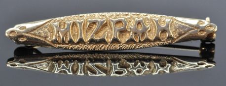 A 9ct gold hallmarked Mizpah bar brooch. Lozenge form with raised lettering and chase decoration.
