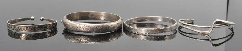 A group of four silver bangle bracelets to include a 1966 Birmingham hallmarked bangle having a push