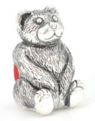 A silver plated pincushion in the form of a teddy bear with a red velvet cushion to the rear. Weighs