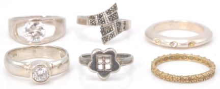 A collection of 6 silver rings to include a silver band set with 3 stones, a silver crossover band