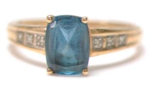 A stamped 375 9ct gold ladies dress ring set with a rectangular cut blue stone with three accent