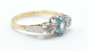 A hallmarked 18ct gold ring set with a central oval cut blue stone flanked by two illusion set white