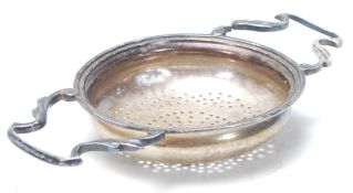 A silver hallmarked 1920's tea strainer having shaped twin handles with pierced holes. Hallmarked