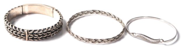 A group of three silver bangle bracelets to include a woven design band bangle (6.5 cm interior