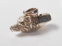 A stamped sterling silver whistle in the form of a dog being set with yellow glass eyes with a