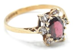 A hallmarked 9ct gold ladies dress ring being set with an oval cut red stone surrounded by six white