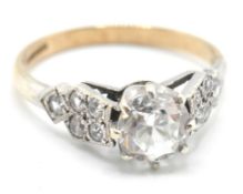 A stamped 9ct gold ring being set with a round cut white stone having white metal shoulders set with