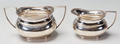 A 1920’s silver hallmarked milk jug and sugar bowl having flat band handles and shaped rim, raised