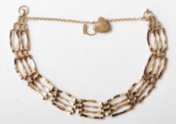 A hallmarked 9ct gold gate link bracelet having a safety chain and heart padlock. Hallmarked London.